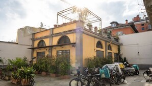 Un patio con un edificio amarillo, plantas en macetas y bicicletas.