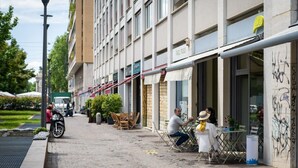 Katu, jossa on ulkona olevia istumapaikkoja, rakennus, jossa on kyltti, ja pysäköity moottoripyörä.