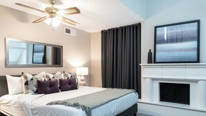 Ein modernes Schlafzimmer mit Bett, Deckenventilator, Kamin und großem Fenster.