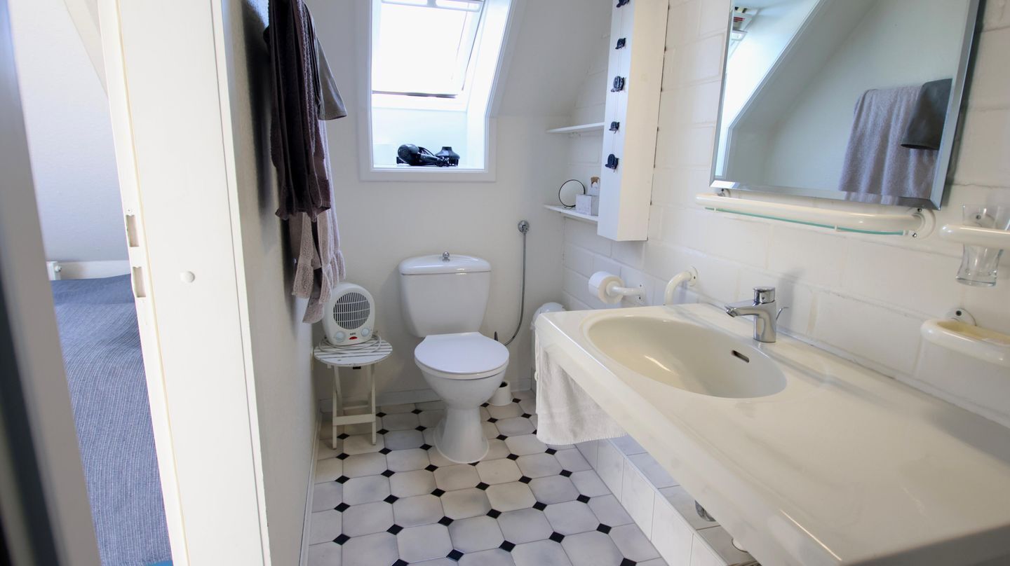 A bathroom with a white toilet, a white sink, and a bathtub. There is a window above the toilet and a mirror above the sink.