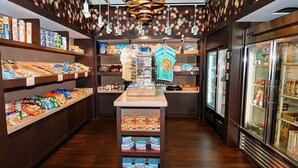 L’intérieur d’un magasin, avec des étagères remplies d’en-cas, un présentoir central et un rayon réfrigéré.