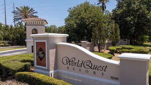 Une enseigne pour le World Quest Resort, avec une tour décorative et des jardins bien entretenus.