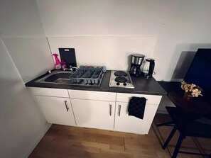 Eine kleine Küchenzeile mit Spüle, Herd und Kaffeemaschine.