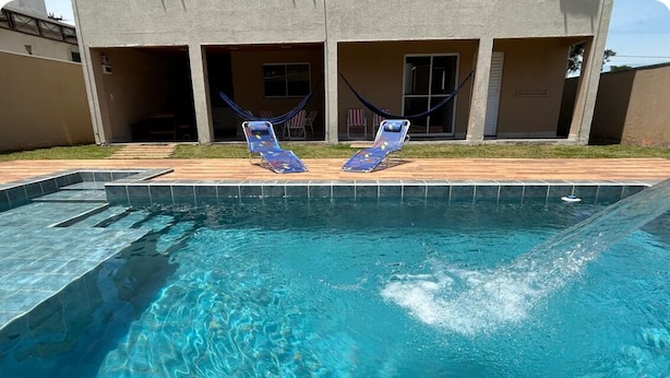Piscina com duas espreguiçadeiras e uma rede.