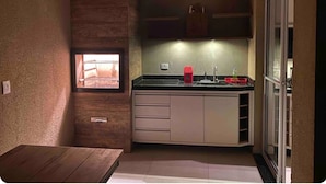Uma cozinha compacta com teto de madeira, janela e pia embutida.