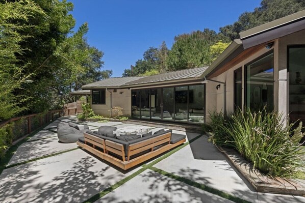 A modern house with a patio area featuring a wooden bench and a small table.