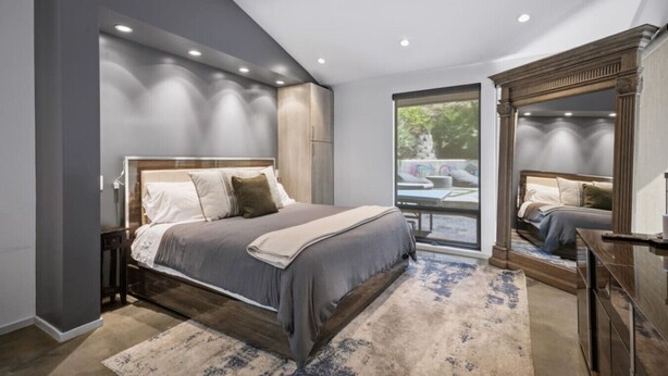 Een moderne slaapkamer met een groot bed, een inbouwkleerkast en een groot raam met uitzicht op de omgeving.