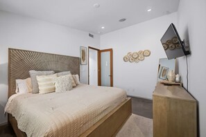 Ein Schlafzimmer mit Bett, Nachttisch und einem an der Wand befestigten Fernseher.