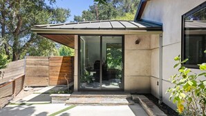 Een modern huis met een glazen deuropening, een houten omheining en een verharde oprit.