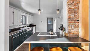 Una cocina moderna con armarios oscuros, una isla central y lámparas colgantes.