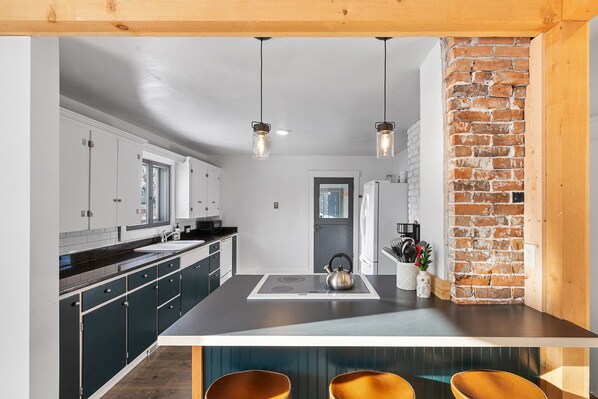 Enjoy cooking in this well-equipped kitchen with a central island, stainless steel kettle, and ample counter space.