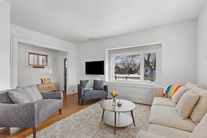 Relax in this inviting space with a comfortable sofa, round coffee table, and large window offering a view of the outdoors.