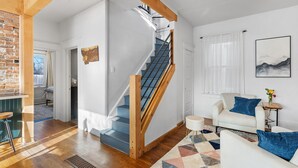 Una sala moderna con una escalera de madera, un sofá blanco y una mesa de centro.