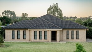A two-story brick house with a dark tiled roof, multiple windows, and a front door. - Bellevue Holiday House (Moore Creek)