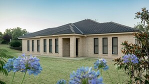 A single-story house with a flat roof, rectangular windows, and a brick facade. - Bellevue Holiday House (Moore Creek)
