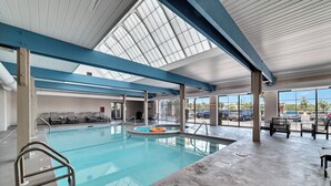 An indoor swimming pool with a skylight ceiling, lounge chairs, and a view of the parking lot. - BEACHFRONT, FAMILY FRIENDLY, INDOOR/OUTDOOR POOL & HOT TUB (Orange Beach)