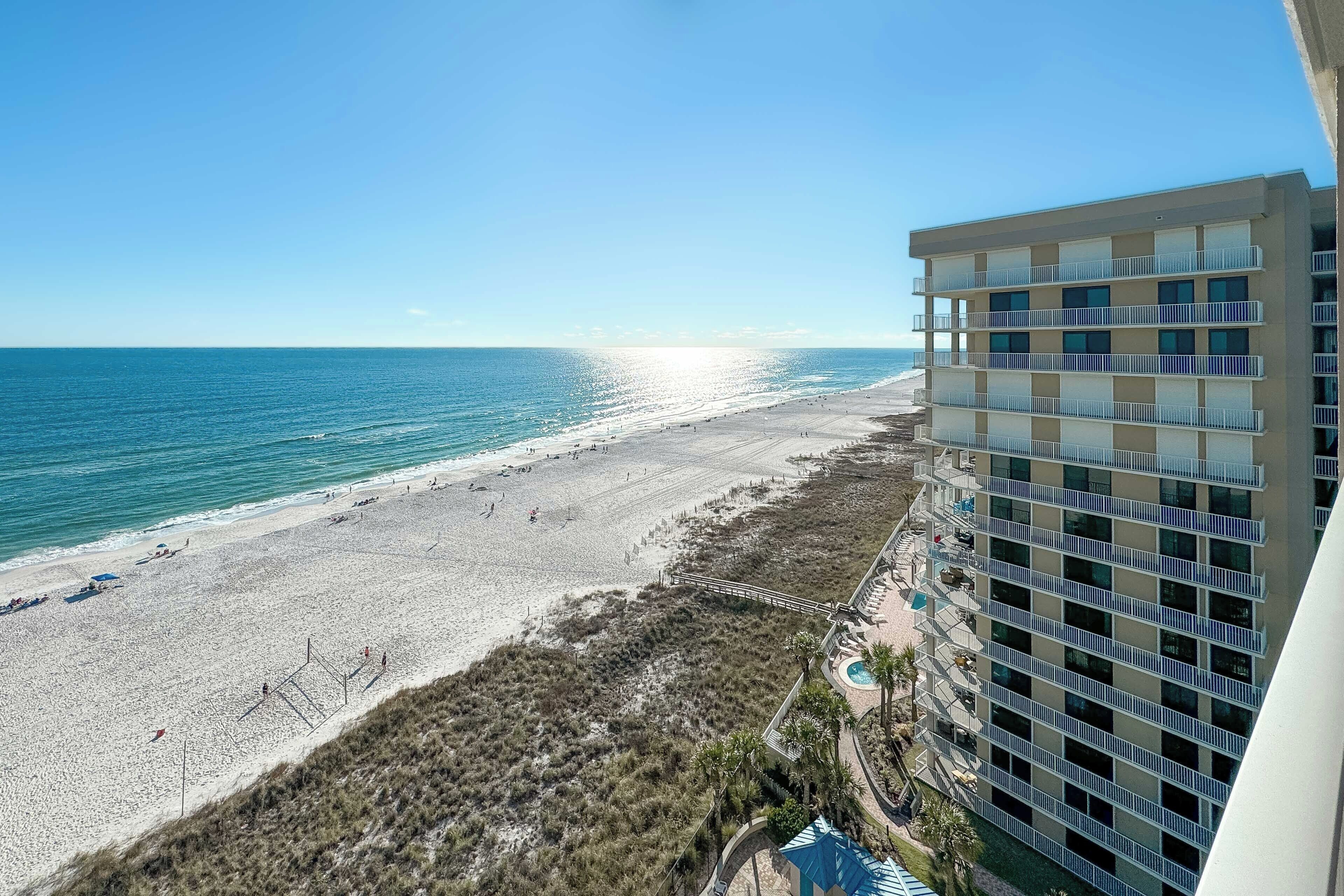 A beachfront hotel with a long balcony overlooking the ocean, a pool area, and a beach.