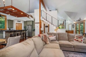 A modern interior with a kitchen, dining area, and a staircase leading to an upper level.