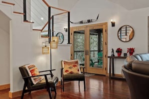 A modern interior with a staircase, two chairs, a sofa, and a dining area.