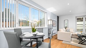 A modern living room with a dining area, large windows, and a view of the outside. - Modern 2 Bedroom Apartment - Jewellery Quarter - Pet Friendly (Birmingham)