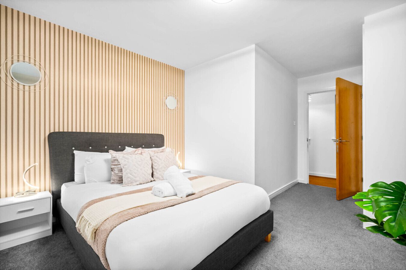 A modern bedroom with a bed, bedside table, and a potted plant.