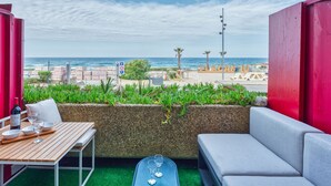 A balcony with a view of the beach, a table with glasses, and a sofa. - Primavéra by Interhome (Lacanau)