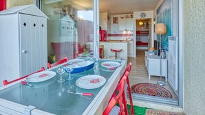 A dining area with a glass table, red chairs, and a white cabinet. - Primavéra by Interhome (Lacanau)