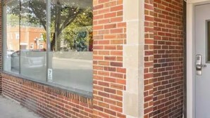 Un bâtiment à la façade en briques, doté de grandes fenêtres et d’une porte équipée d’un clavier pour l’ouverture à code.