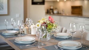 A dining table set with plates, glasses, and a centerpiece of flowers.