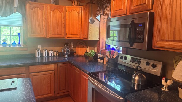 Una cocina con armarios de madera, estufa de acero inoxidable y microondas.
