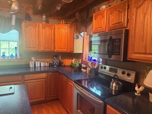 Una cocina con armarios de madera, estufa de acero inoxidable y microondas.