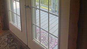 Habitación con un ventanal y una puerta, que dan a una terraza exterior con barandilla.