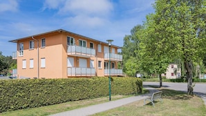 Ein mehrstöckiges Gebäude mit Balkonen, einem gepflasterten Weg und einer Hecke.