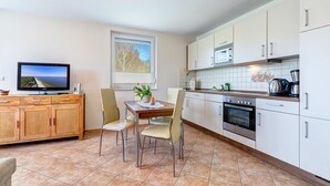 A modern kitchen with a dining area, a TV, and a window with a view.