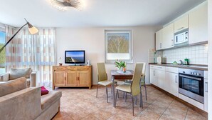 A modern kitchen with a dining area, a TV, and a sofa.