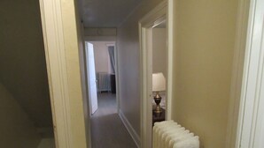 A narrow hallway with a radiator on the right and a door leading to another room.