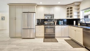Una cocina moderna con electrodomésticos de acero inoxidable, armarios blancos y una encimera negra.