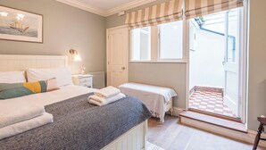 Une chambre à coucher avec un lit, une table de chevet, une lampe et une fenêtre donnant sur l’extérieur.