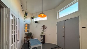 A narrow hallway with a dining table and chairs, a hanging light fixture, a window, and a door. - Historic Bakery Storefront-Private Yard & Laundry (Albuquerque)