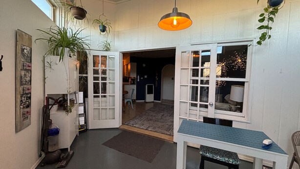 A room with a dining table, chairs, hanging plants, and a view into another room. - Historic Bakery Storefront-Private Yard & Laundry (Albuquerque)
