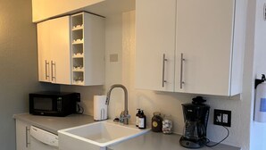 A compact kitchen with a microwave, sink, coffee maker, and storage cabinets. - Historic Bakery Storefront-Private Yard & Laundry (Albuquerque)
