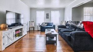 A living room with a TV, a sofa, a coffee table, and a cabinet. - Benedictine Theme 2br 1ba (Atchison)