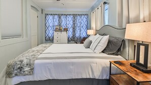 Ein ordentlich eingerichtetes Schlafzimmer mit Bett, Nachttisch, Lampe und Deckenventilator.
