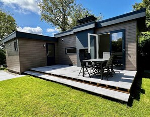 Una casa moderna con un patio, un comedor con sillas y una mesa, y una puerta.
