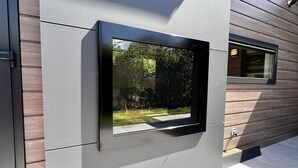 Un bâtiment moderne doté d’une grande fenêtre offrant une vue sur un jardin.