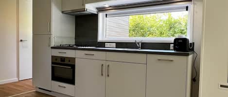 A modern kitchen with white cabinets, a built-in oven, a stove, and a window above the sink.