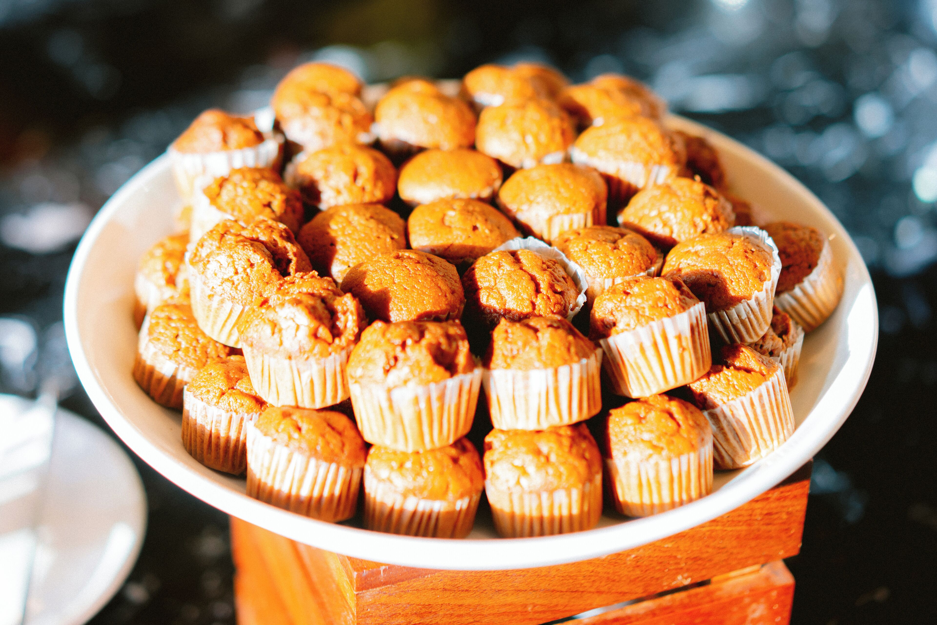 A plate of muffins arranged in a circular pattern on a wooden stand.