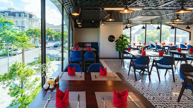 A restaurant with a view of the street, tables with red napkins, and blue chairs.