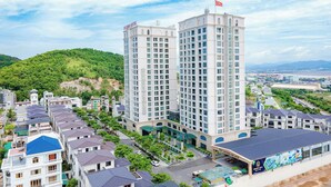 A high-rise hotel with multiple floors, a flag on top, and a view of surrounding residential buildings and greenery.
