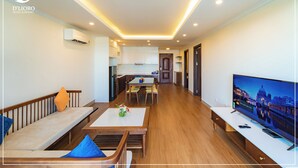 A modern hotel room with a dining area, a TV, and a view of a cityscape.